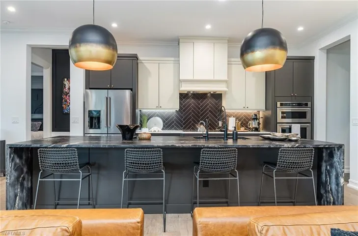 Kitchen featuring light hardwood / wood-style floors, dark stone counters, a kitchen bar, and stainless steel appliances