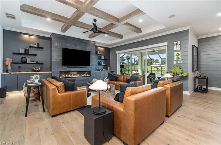 Living room with beamed ceiling, light hardwood / wood-style floors, coffered ceiling, and a fireplace