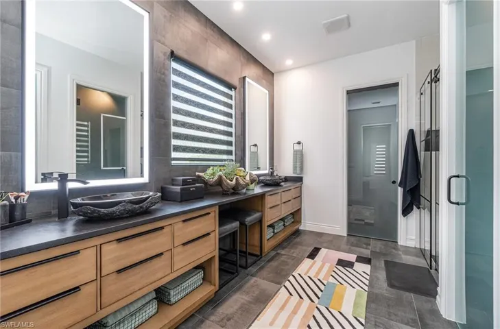 Bathroom featuring tile walls, a shower with shower door, and vanity