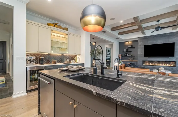 Kitchen with beamed ceiling, wine cooler, sink, light hardwood / wood-style flooring, and dark stone counters