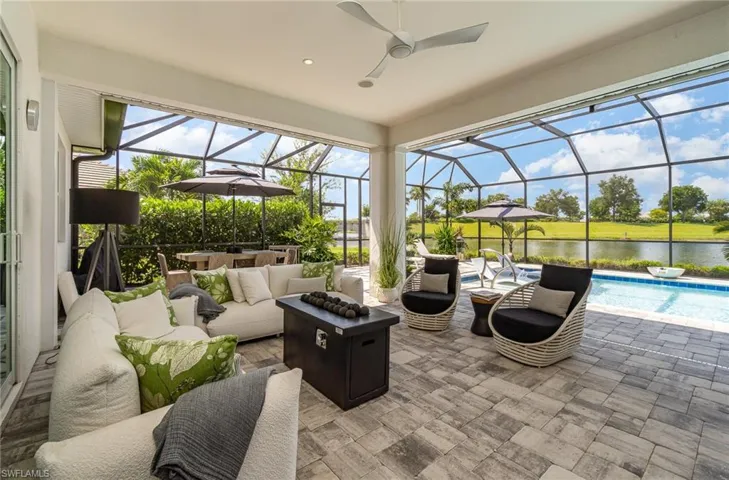 View of patio with ceiling fan, outdoor lounge area, glass enclosure, and a water view