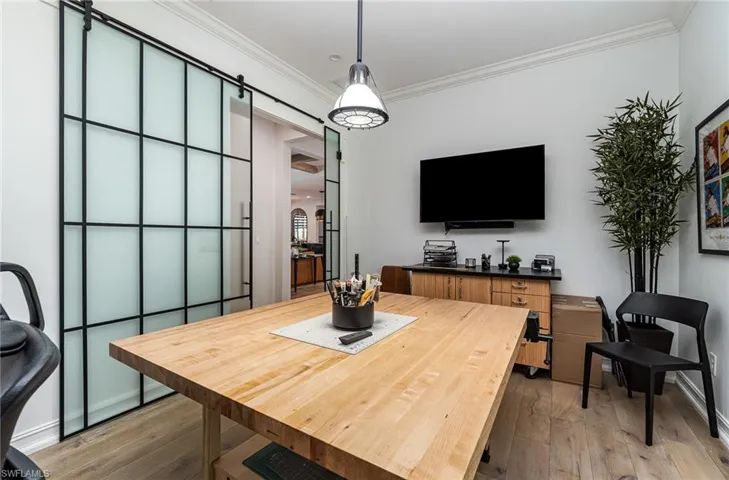 Dining space featuring ornamental molding, hardwood / wood-style flooring, and a barn door