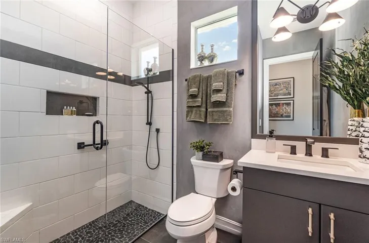 Bathroom featuring vanity, a shower with shower door, and toilet