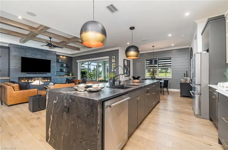 Kitchen with coffered ceiling, a large island, plenty of natural light, and sink