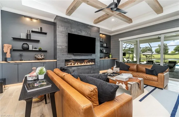Living room featuring beamed ceiling, light hardwood / wood-style flooring, coffered ceiling, a fireplace, and crown molding
