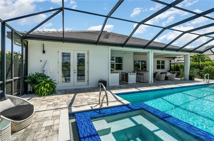 View of swimming pool with a lanai, a patio, an in ground hot tub, and french doors