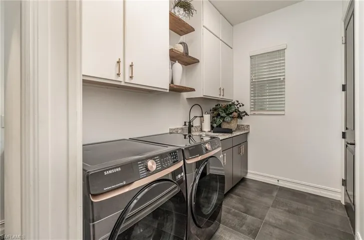 Washroom with sink, washing machine and clothes dryer, and cabinets