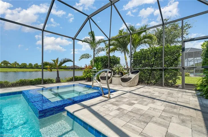 View of swimming pool with a lanai, an in ground hot tub, a water view, and a patio area