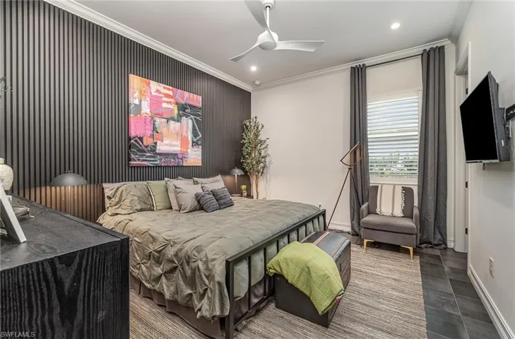 Tiled bedroom with ceiling fan and crown molding