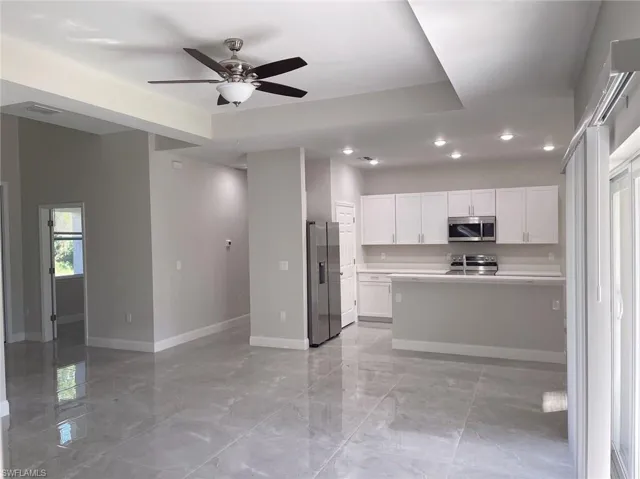 Kitchen with stainless steel appliances, white cabinets, ceiling fan, and light tile floors