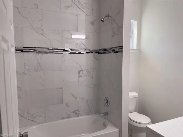 Full bathroom featuring tiled shower / bath, vanity, and toilet
