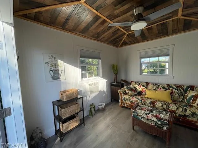 Living room featuring lofted ceiling, crown molding, ceiling fan, wood-type flooring, and wood ceiling