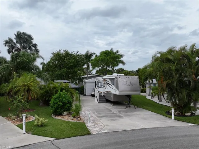 View of front of property featuring a garage, a front lawn, and an outbuilding