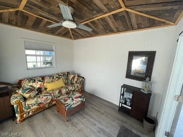 Living room featuring ornamental molding, vaulted ceiling, ceiling fan, wooden ceiling, and hardwood / wood-style floors