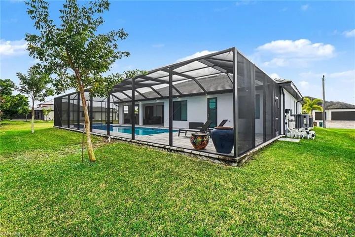 Rear view of house with a sunroom, an outdoor pool, glass enclosure, and a yard