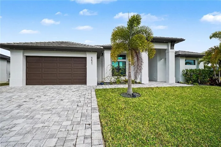 Prairie-style home with a front lawn, an attached garage, decorative driveway, and stucco siding