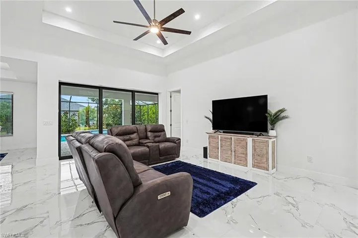 Living area with a ceiling fan, a tray ceiling, and recessed lighting