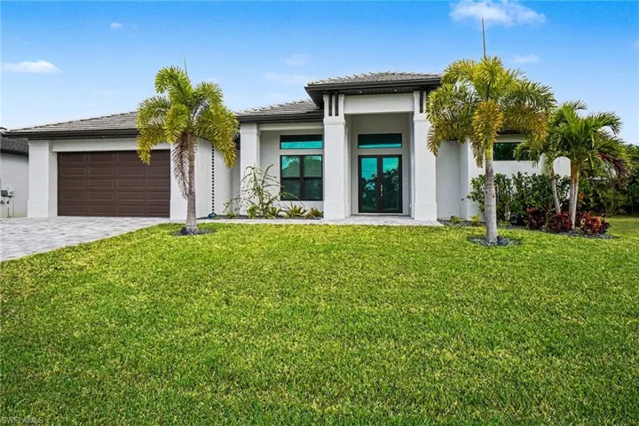 Prairie-style home featuring french doors, decorative driveway, a front lawn, and stucco siding