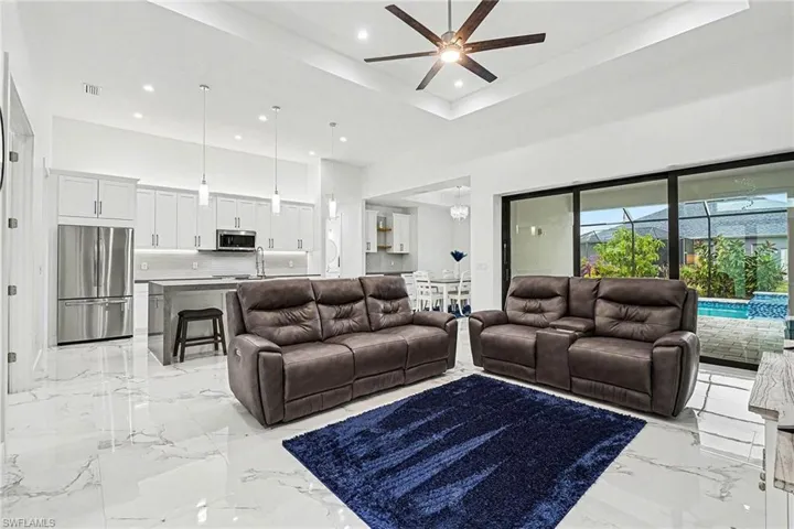 Living area with a raised ceiling, ceiling fan, and recessed lighting