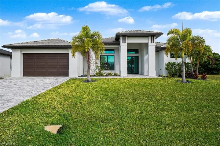 Prairie-style house with decorative driveway, a front yard, stucco siding, an attached garage, and a tiled roof