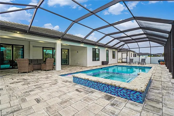 Combined pool / hot tub featuring a sunroom, a patio, and glass enclosure