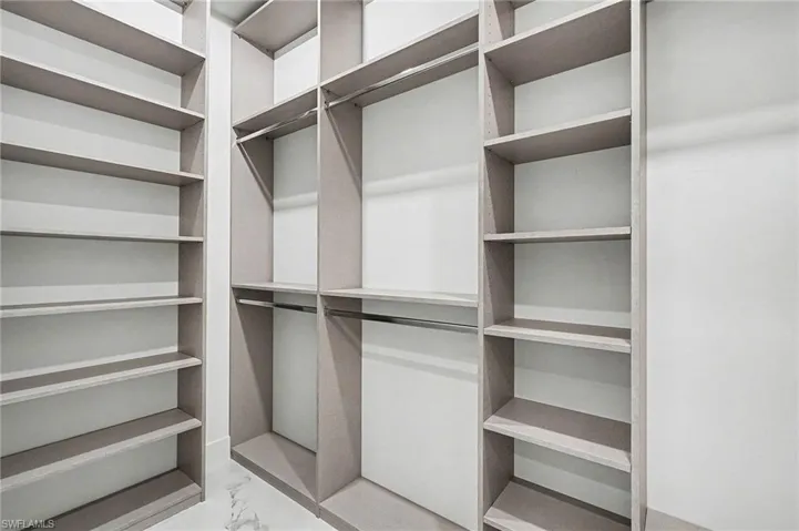 Walk in closet featuring light marble finish flooring