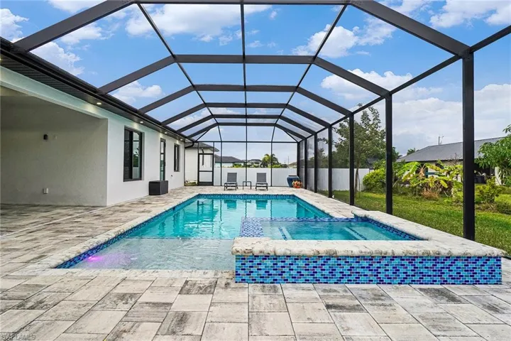 Relaxing pool / spa with a sunroom, a lanai, and a patio
