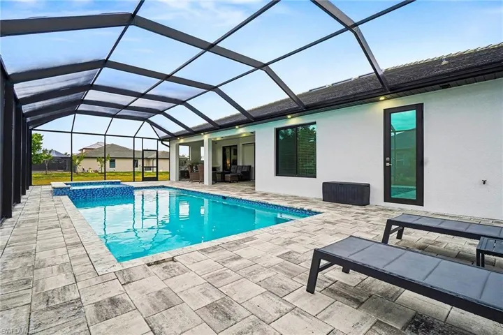 Integrated pool / hot tub featuring a sunroom, glass enclosure, a patio area, and outdoor seating