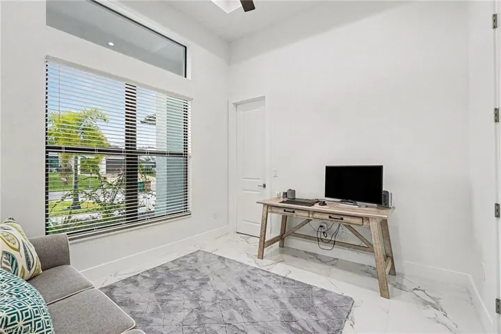 Office space with light marble finish floors and a ceiling fan