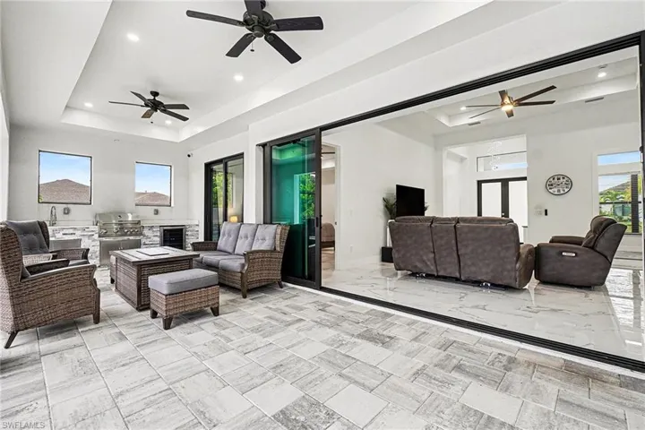 Living area with a ceiling fan, a raised ceiling, recessed lighting, and beverage cooler