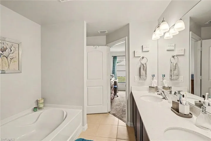 Bathroom featuring a dual vanity with white countertops, undermount sinks, and a large mirror