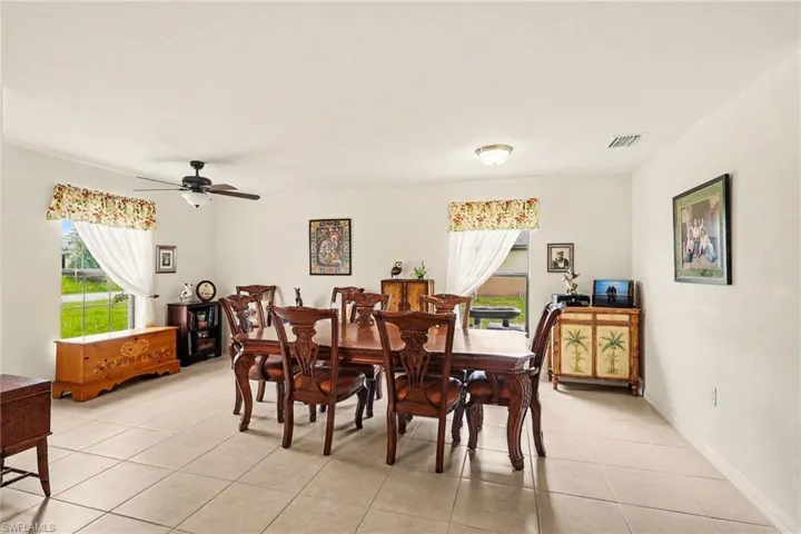Bright dining area featuring tile flooring, neutral wall tones, and two windows
