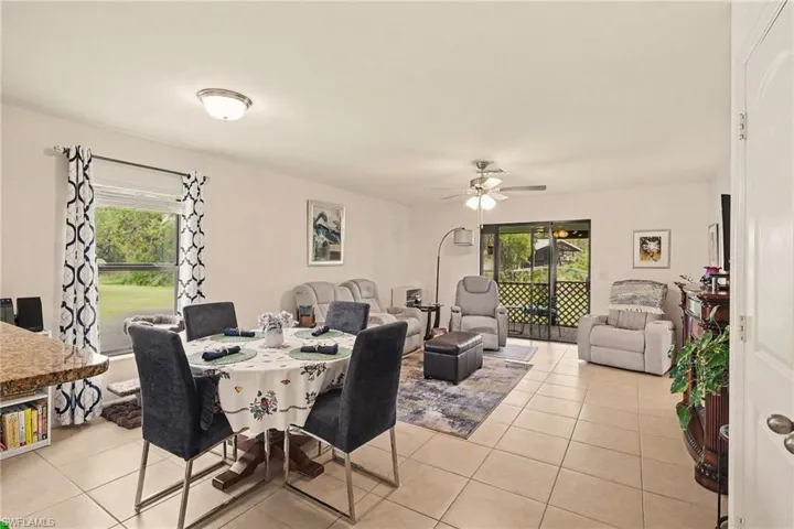 Open concept living area with light tile flooring, an overhead ceiling fan, and a screened patio