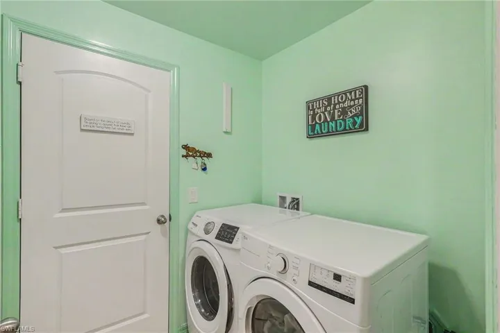 Dedicated laundry area featuring a white paneled door, light green walls, and hookups for a washer and dryer
