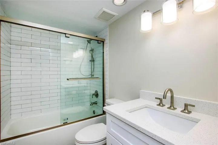 Full bathroom with combined bath / shower with glass door, vanity, and toilet