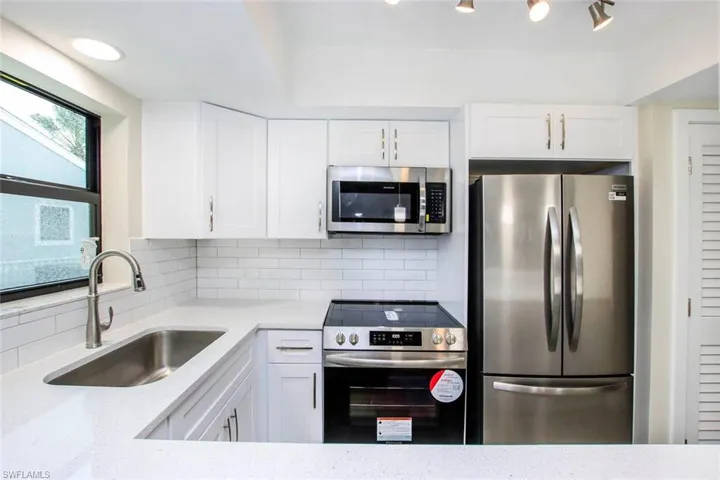 Kitchen with white cabinetry, sink, tasteful backsplash, and stainless steel appliances