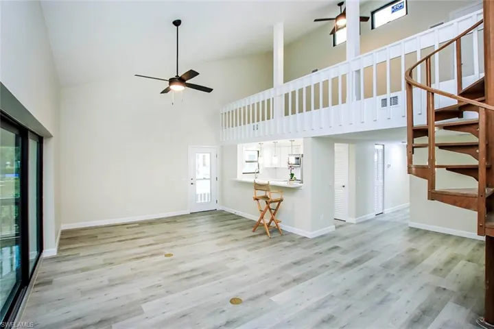Unfurnished living room with high vaulted ceiling, ceiling fan, and light hardwood / wood-style floors