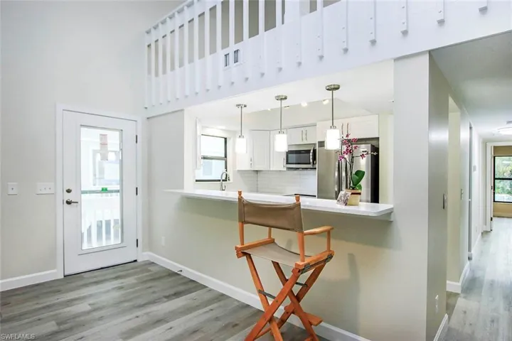 Kitchen featuring hanging light fixtures, appliances with stainless steel finishes, white cabinetry, and light hardwood / wood-style flooring