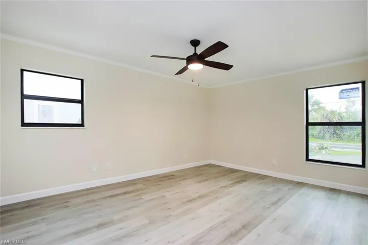 Empty room featuring ornamental molding, light wood-type flooring, and ceiling fan