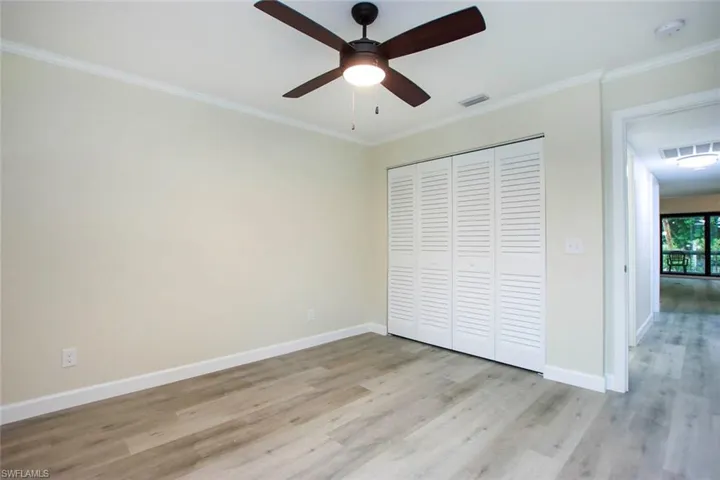 Unfurnished bedroom featuring ornamental molding, a closet, ceiling fan, and light hardwood / wood-style flooring