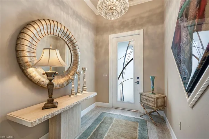 Doorway to outside with a chandelier, light wood-style floors, and baseboards