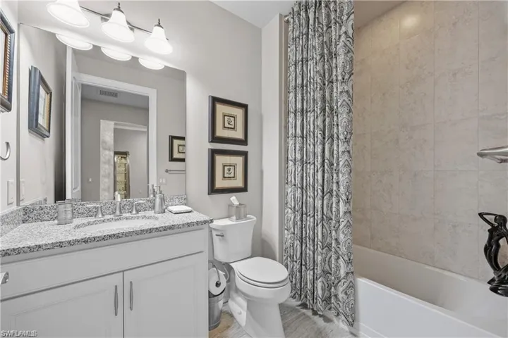 Bathroom featuring vanity and shower / bathtub combination with curtain