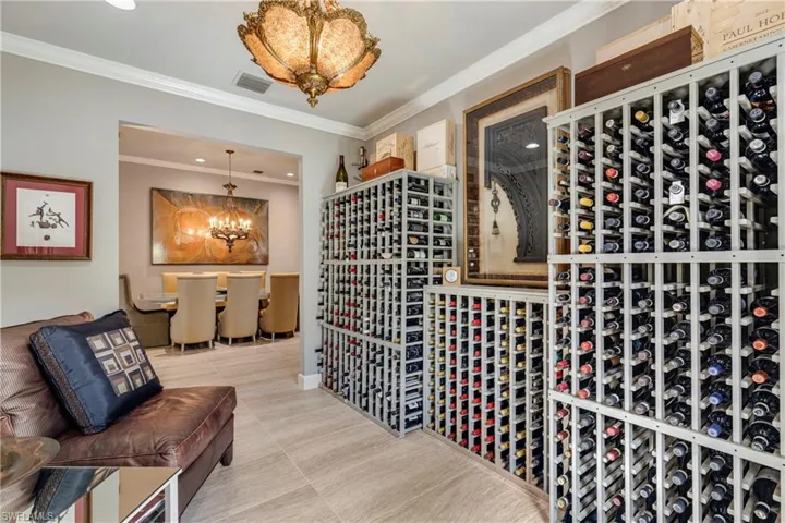 Wine cellar featuring tile patterned flooring, visible vents, a chandelier, and crown molding