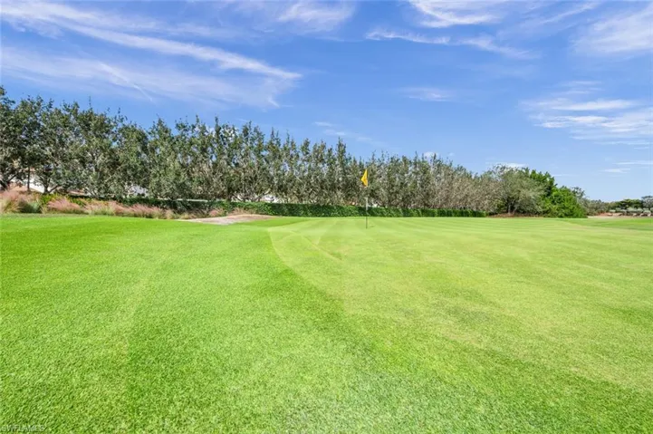 View of green lawn featuring view of golf course and view of scattered trees