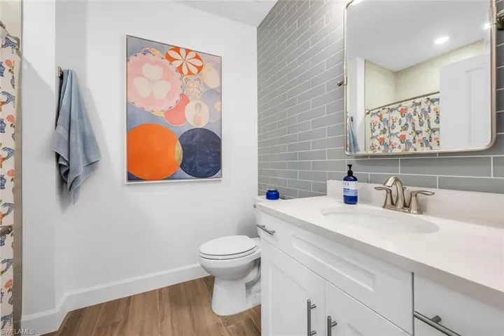 Full bath featuring a shower with curtain, vanity, light wood-type flooring, and tile walls