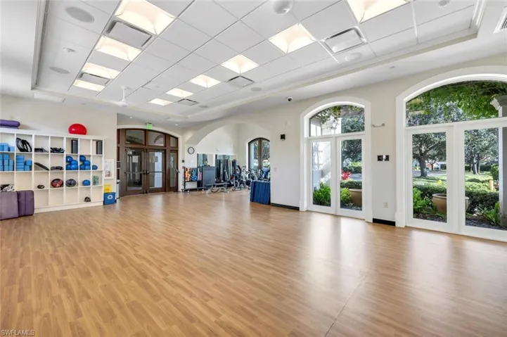 Workout area featuring a drop ceiling, a raised ceiling, and french doors