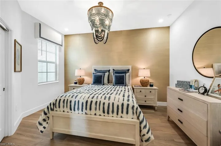 Bedroom featuring wood finished floors, suspended lighting, and an accent wall