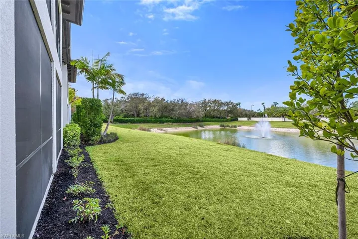 View of grassy yard with a water view and a sunroom