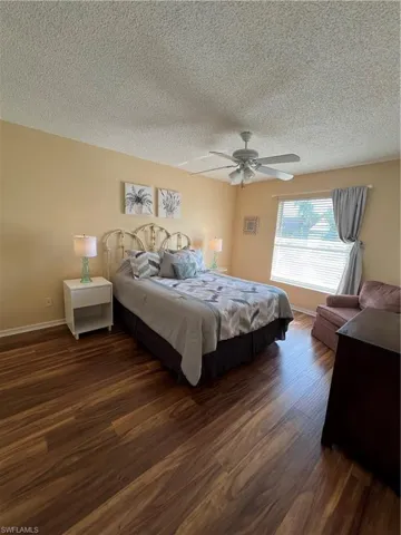 Room featuring wood-finish flooring, a ceiling fan, and a window with blinds