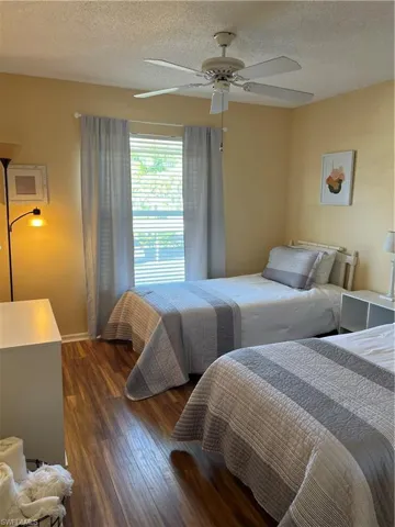 Room featuring wood-finish flooring, a window with horizontal blinds, and a ceiling fan with integrated lighting